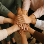 Viele Frauenhände die aufeinanderliegen und Gemeinsamkeit symbolisieren