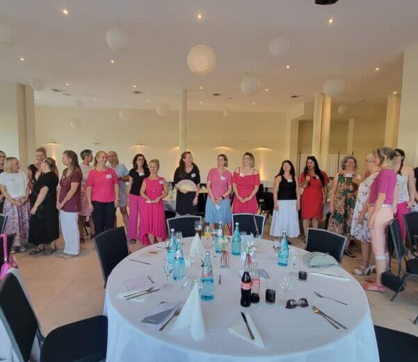 gruppe von Frauen/ Unternehmerinnen stehen in einer Reihe und sind sommerlich gekleidet in Beerenfarben