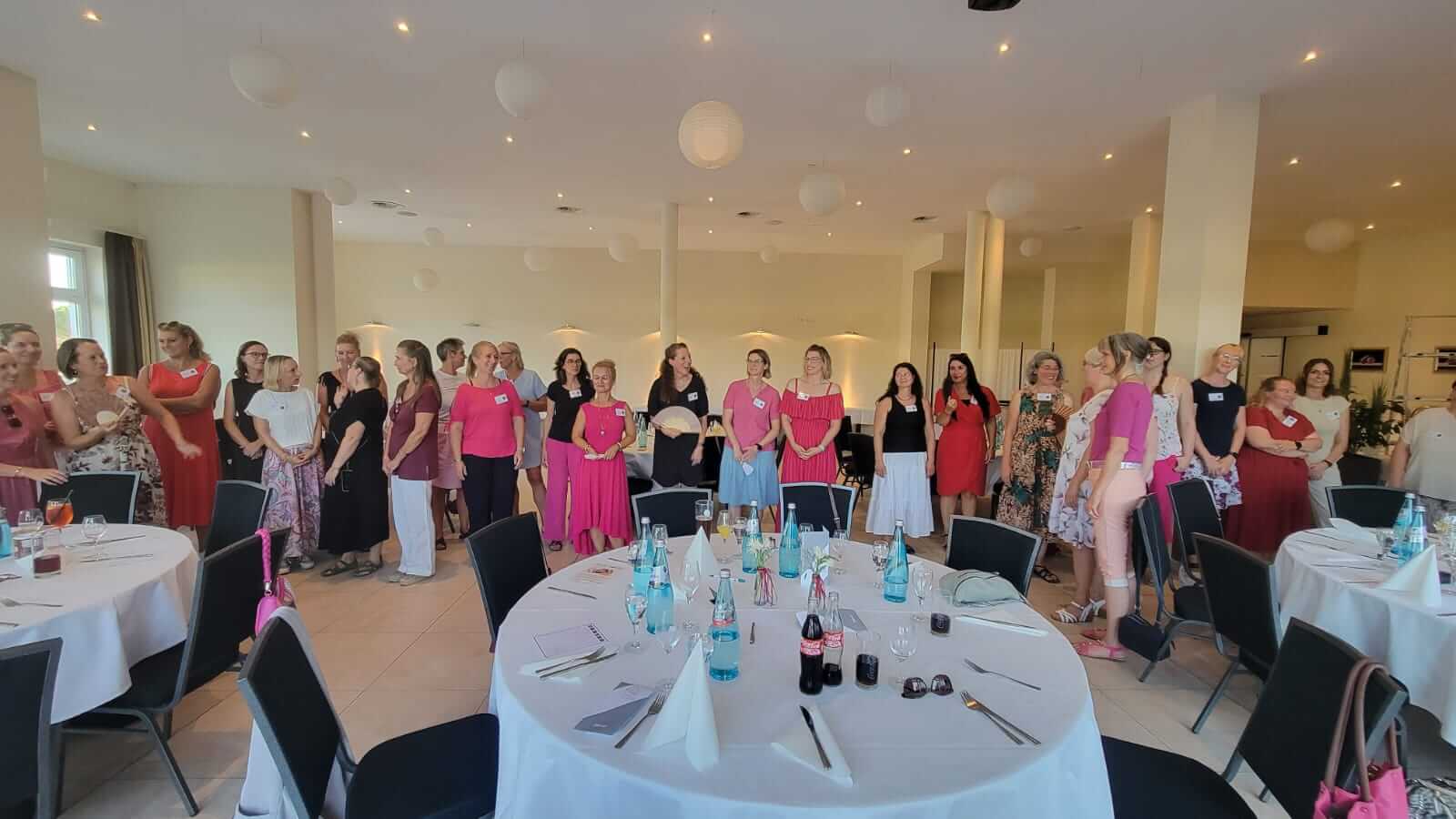 gruppe von Frauen/ Unternehmerinnen stehen in einer Reihe und sind sommerlich gekleidet in Beerenfarben
